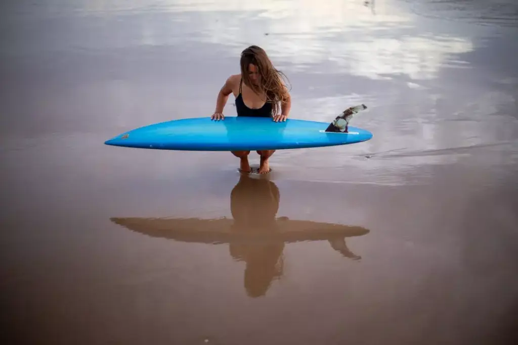Surferin mit Surfboard am Strand